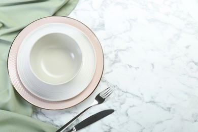 Photo of Clean plates, bowl and cutlery on white marble table, flat lay. Space for text