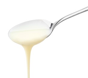 Photo of Pouring condensed milk from metal spoon isolated on white