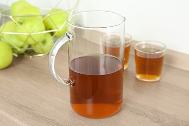 Photo of Jug with fresh apple juice on wooden table