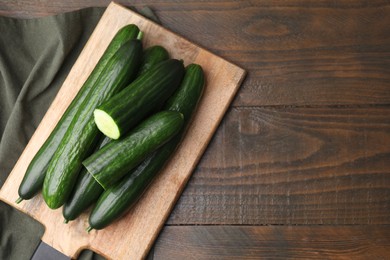 Photo of Fresh cucumbers on wooden table, top view. Space for text
