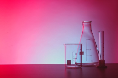 Photo of Empty chemistry laboratory glassware on table against color background