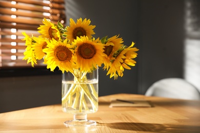 Photo of Bouquet of beautiful sunflowers on table in room