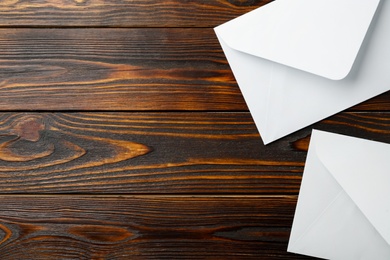 Photo of White paper envelopes on wooden background, flat lay. Space for text