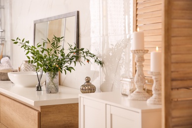 Photo of Vase with beautiful branches near vessel sink in bathroom. Interior design