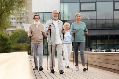 Photo of Group of senior people performing Nordic walking outdoors. Low angle view