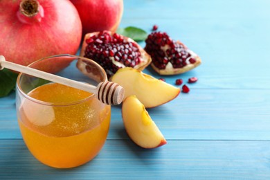 Photo of Honey, pomegranate and apples on light blue wooden table, closeup. Rosh Hashana holiday