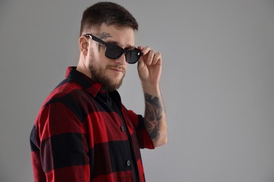 Photo of Handsome hipster man wearing stylish sunglasses on light grey background. Space for text