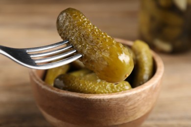 Photo of Eating tasty pickled cucumber at table, closeup