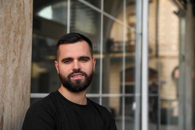 Photo of Portrait of handsome bearded man near building outdoors. Space for text