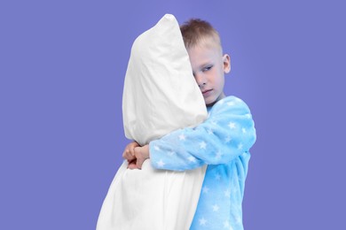 Photo of Sleepy boy with pillow on purple background. Insomnia problem