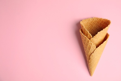 Photo of Empty wafer ice cream cones on pink background, flat lay. Space for text