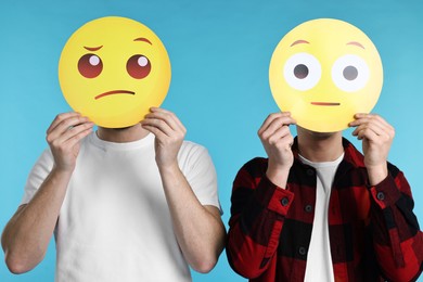 Photo of People covering faces with emoticons on light blue background