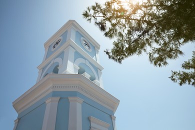 Photo of Beautiful tower with clock against blue sky, low angle view