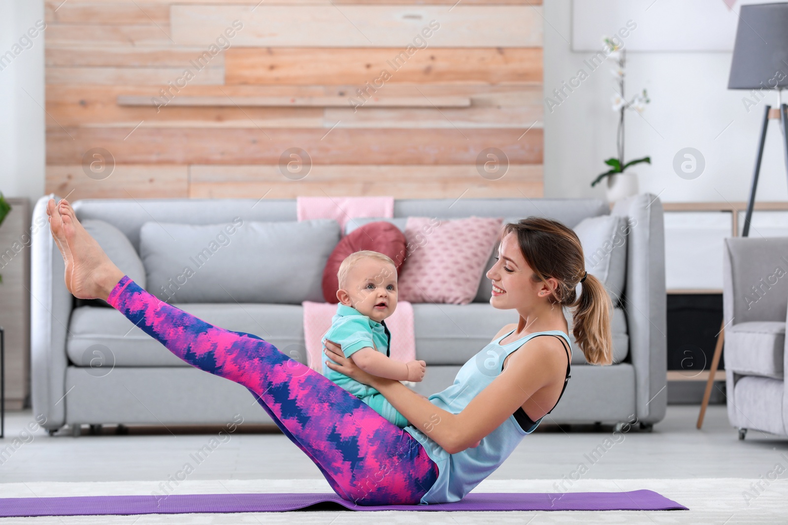 Photo of Young sportive woman doing exercise with her son at home. Fitness training