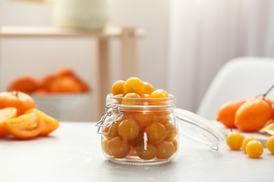 Photo of Pickling jar with fresh yellow tomatoes on light kitchen table