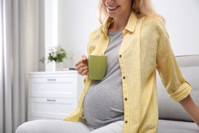 Photo of Beautiful pregnant woman drinking tea at home, closeup