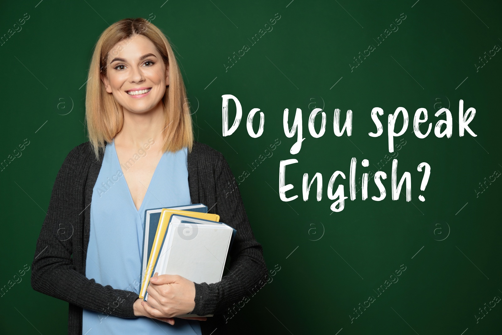 Image of Beautiful English teacher with books near chalkboard