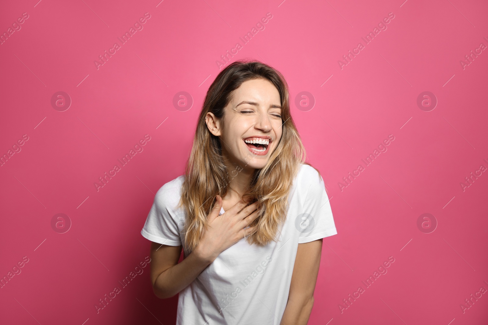 Photo of Cheerful young woman laughing on pink background