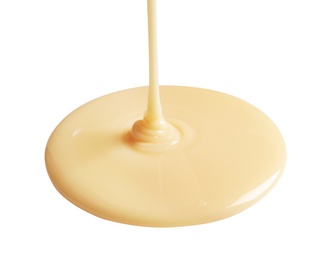 Photo of Tasty pouring condensed milk on white background. Dairy product