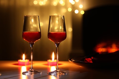 Photo of Glasses of wine and candles on table against blurred lights. Romantic dinner