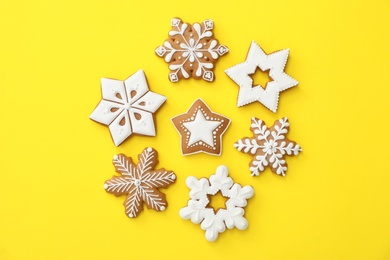 Photo of Christmas snowflake shaped gingerbread cookies on yellow background, flat lay