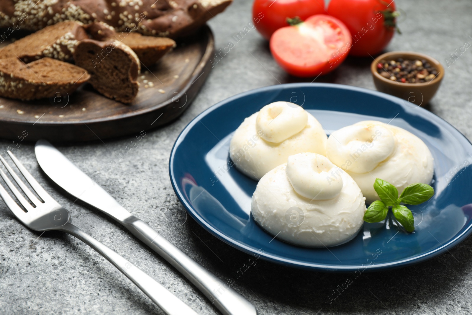 Photo of Delicious burrata cheese with basil on grey table