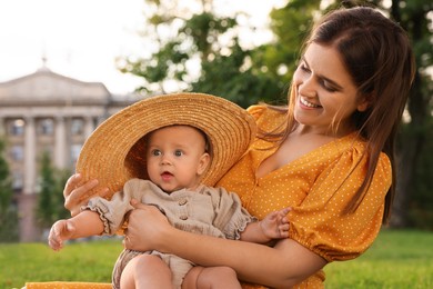 Photo of Happy mother with adorable baby sitting on green grass in park