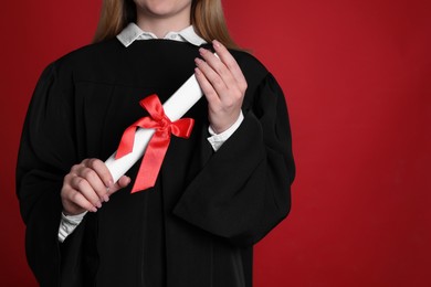 Photo of Student with diploma on red background, closeup