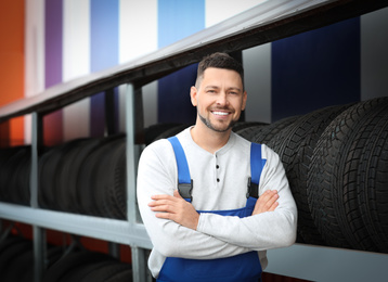 Mechanic near rack with car tires at service station