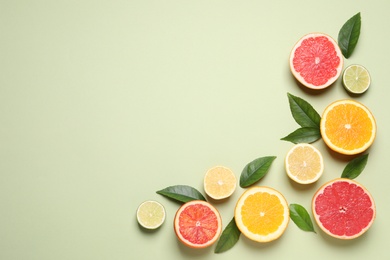 Photo of Fresh juicy citrus fruits with green leaves on light background, flat lay. Space for text