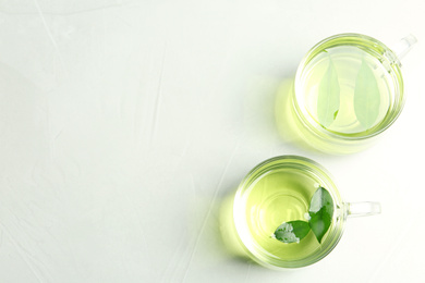Photo of Cups of aromatic green tea on light table, flat lay. Space for text