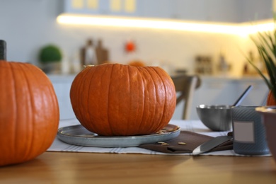 Photo of Fresh ripe pumpkins on table in kitchen. Halloween celebration