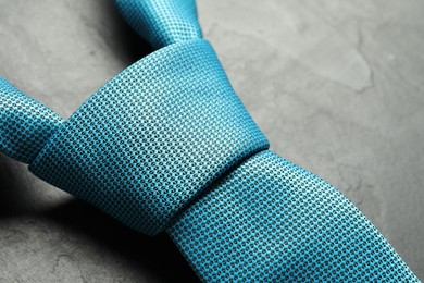 Photo of One light blue necktie on grey textured table, closeup