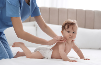 Photo of Orthopedist and cute baby on white bed