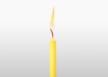 Image of One burning church candle on light background