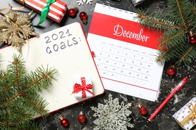 Photo of Calendar, notebook with inscription 2021 Goals near Christmas decor on dark grey table, flat lay