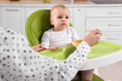 Photo of Mother feeding her cute little baby with healthy food at home