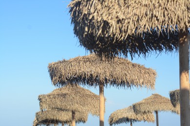 Beautiful straw beach umbrellas against blue sky