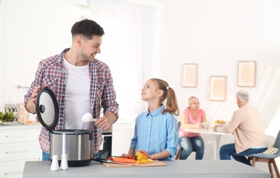 Photo of Father and daughter preparing food with modern multi cooker in kitchen