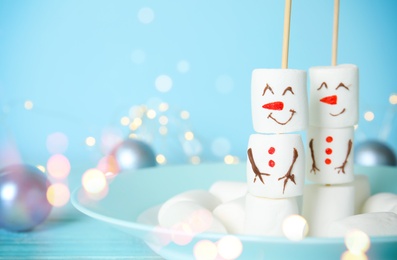 Image of Funny snowmen made of marshmallows in plate, space for text. Bokeh effect 