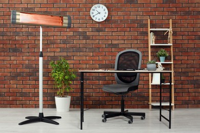 Photo of Electric infrared heater near brick wall in stylish room