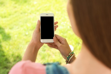 Photo of Woman using smartphone with blank screen outdoors, closeup. Mock up for design