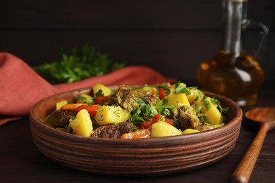 Photo of Tasty cooked dish with potatoes in earthenware served on wooden table