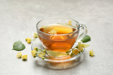 Photo of Cup of tea and linden blossom on light grey table