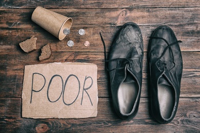Photo of Flat lay composition with word POOR, coins and dirty shoes on wooden background