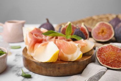 Photo of Tasty melon, jamon and figs served on white marble table
