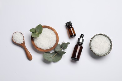 Photo of Aromatherapy products. Bottles of essential oil, sea salt and eucalyptus leaves on white background, flat lay