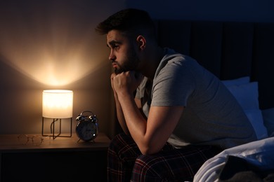 Photo of Frustrated man suffering from insomnia on bed