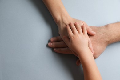 Photo of Parents and child holding hands together on gray background, top view. Space for text