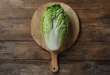 Photo of Cutting board with fresh ripe Chinese cabbage on wooden table, top view